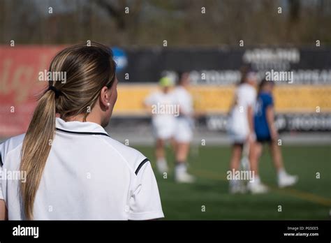 over the shoulder female head coach on sidelines yelling play call to