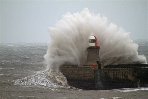 A Large Wave Crashes Into The Lighthouse At The Entrance