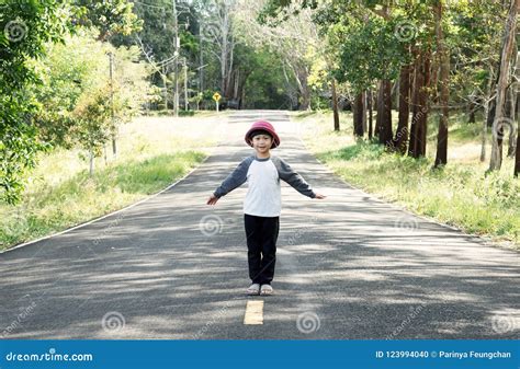 Little Asian Child Standing In The Middle Of The Road Stock Photo