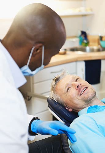 Dental Patient In Chair Smiles Up At Dentist Stock Photo Download