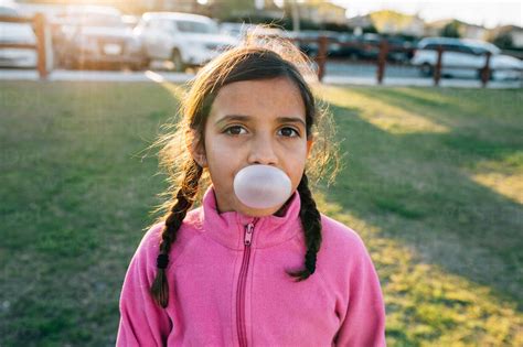 Portrait Of Girl Blowing Bubble Gum While Standing At Park Stock Photo
