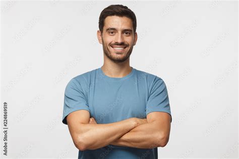 Indoor Portrait Of Young European Caucasian Man Isolated On Gray Background Standing In Blue T