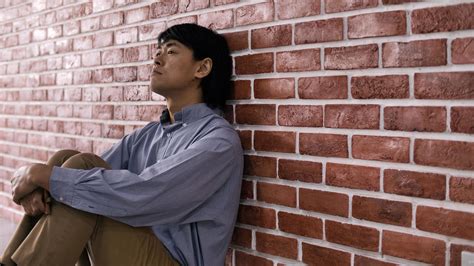 Depressed Young Man Sitting On Floor Against A Wall 11556326 Stock