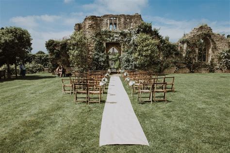 An Outdoor Ceremony Setup With Wooden Chairs And White Runneres In