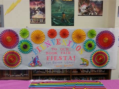 A Book Fair Sign With Paper Fans On The Front And Behind It Is A