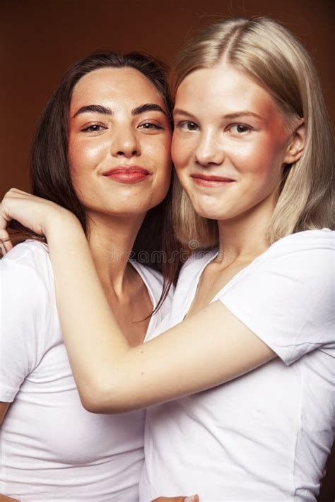 Two Pretty Diverse Girls Happy Posing Together Blond And Brunette On Brown Background