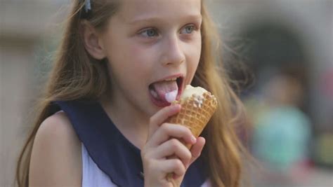 little blonde girl eats licks an ice cream cone on a park bench portrait stock footage video