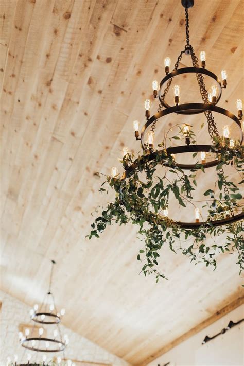 A Chandelier With Greenery Hanging From Its Sides In A Room