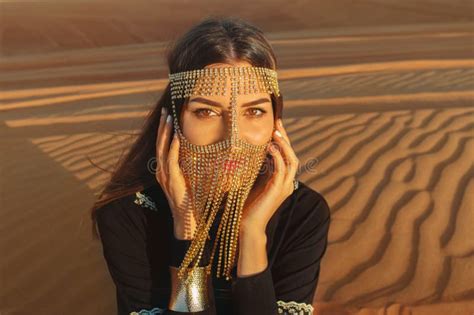 beautiful woman in brilliant burqa mask among the dubai desert at sunset timearabian style