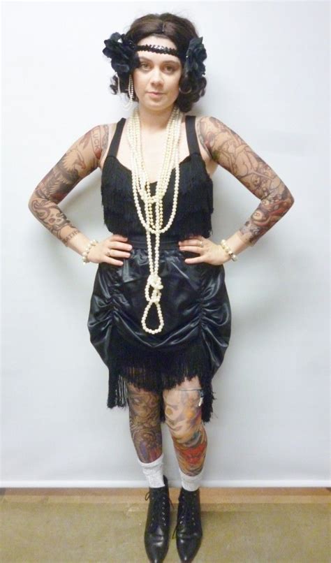 A Woman With Tattoos Wearing A Black Dress And Pearls