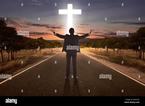 Portrait Of Man Raising Hand While Praying To God With Bright Cross At