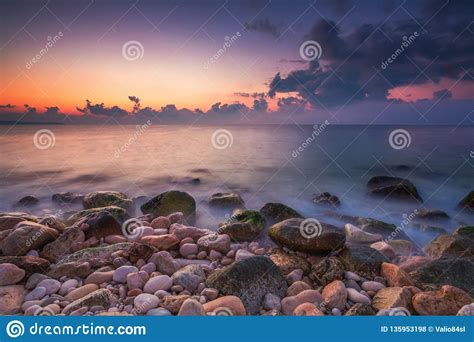 Beautiful Sunrise Over The Sea And Splashing Waves On The Rocks Stock