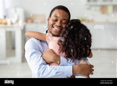 Loving Black Father And Daughter Hugging With Closed Eyes Stock Photo