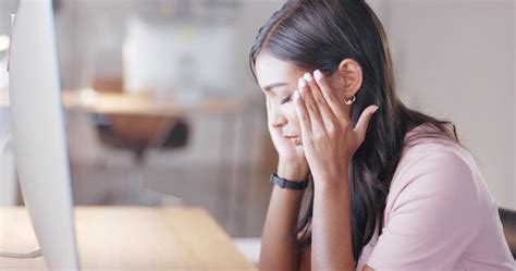 Женщина страдает от головной боли или мигрени во время работы за настольным компьютером в офисе
