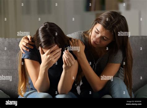 Girl Comforting Her Divorced Friend Sitting On A Couch In The Living