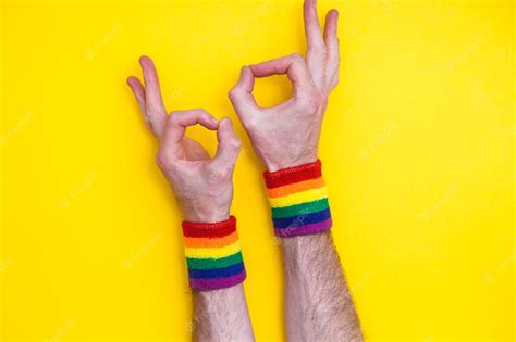 Premium Photo Okay Hand Gesture With Gay Pride Rainbow Flag Wristband On A Yellow Background