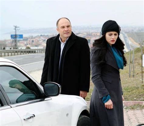 A Man And Woman Standing Next To A White Car