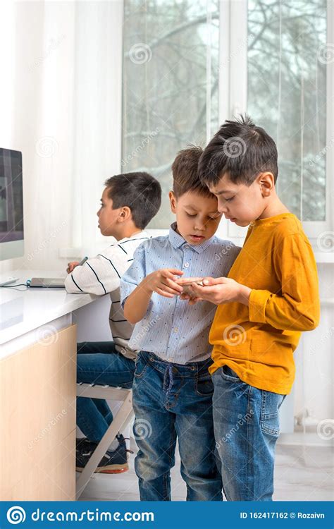 Three Boys Play Games Using Computer And Phone Stock Photo Image Of