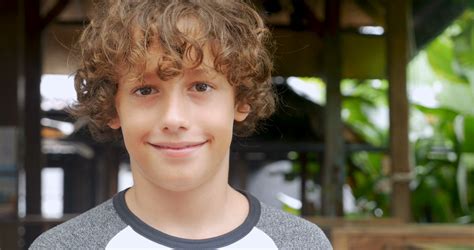 Portrait Of A Cute Young 11 12 Year Old Boy With Curly Hair Smiling And Looking At The Camera