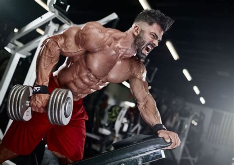 A Man Is Doing Exercises With Dumbbells In The Gym