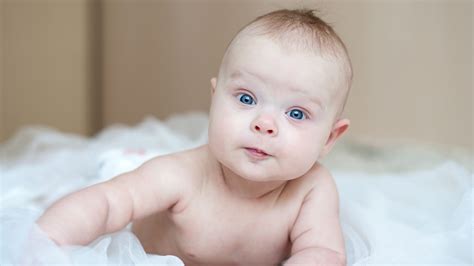 Light Blue Eyes Cute Baby Lying Down On White Cloth Blur Wall
