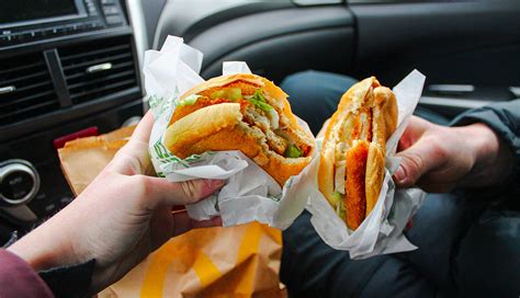 Fast food is a kind of dishes that can be cooked and served within 15 minutes. Hands holding fast food sandwhich