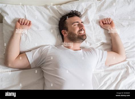 Top View Of Handsome Man Smiling While Sleeping In His Bed At Home