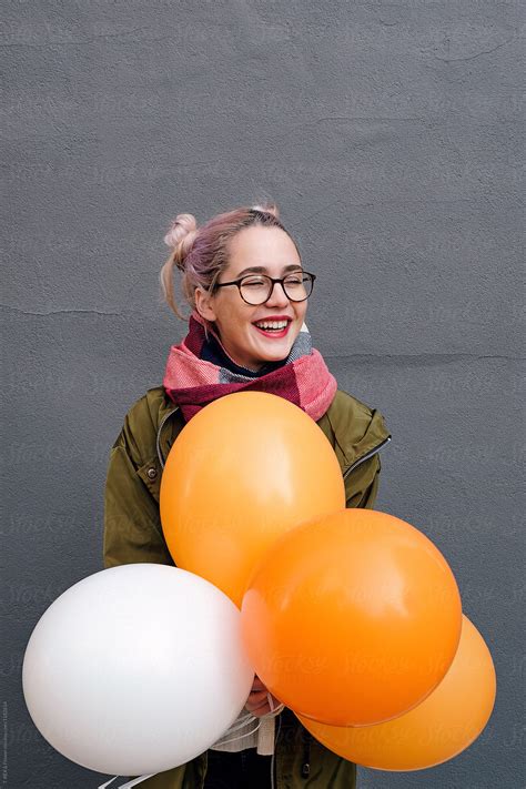 Girl Holding Orange And White Air Balloons Del Colaborador De Stocksy