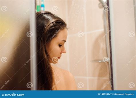 Mujer Joven Desnuda Hermosa Que Sonríe Mientras Que Toma La Ducha En Cuarto De Baño Imagen de