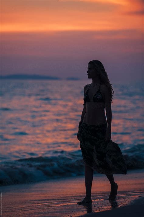 Woman Silhouette Walks On The Beach At Sunset Del Colaborador De