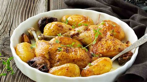 A white bowl filled with potatoes and mushrooms on top of a wooden