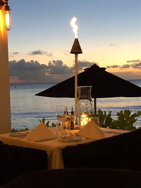An Outdoor Dining Area Overlooking The Ocean At Dusk With Lit Candles