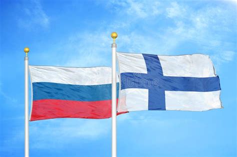Russia And Finland Two Flags On Flagpoles And Blue Cloudy Sky Stock