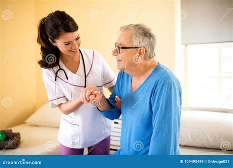 Careful Young Nurse Helps Senior Patient To Stand Up Stock Image