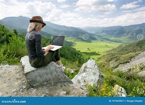 Woman Working on Her Computer on the Top of the Mountain. Remote Work