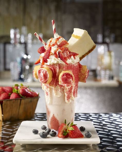 A Drink With Strawberries And Whipped Cream In It Sitting On A Table