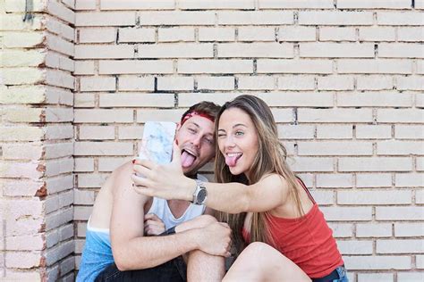 Couple Taking Selfies Against Brick Wall By Stocksy Contributor Ivan Gener Relationship