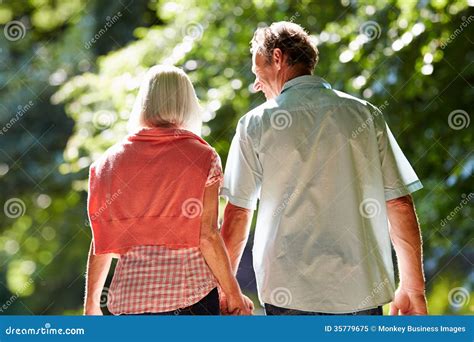 Rear View Of Middle Aged Couple Walking Along Country Lane Stock Image