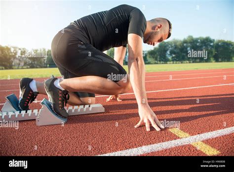 Male Athlete On Starting Position At Athletics Running Track Stock