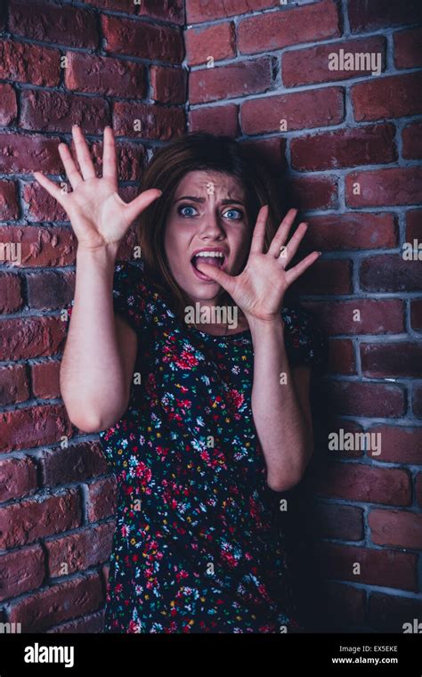 Frightened Young Woman Standing In Corner Of Brick Wall Stock Photo Alamy