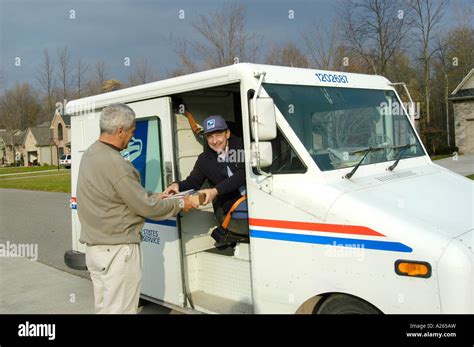 Postal carrier driving a mail truck delivers mail to male home owner