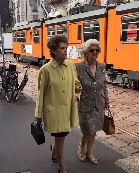two women walking down the street in front of a train