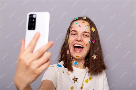 Фотография смеющейся женщины-блогера, покрытой забавными наклейками ...