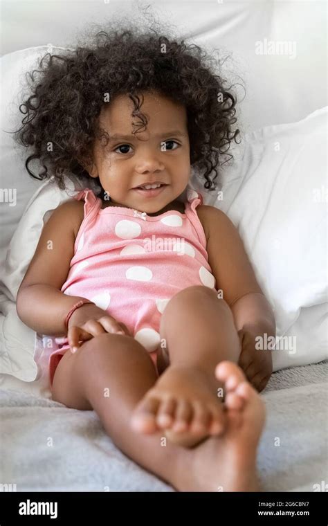Little African American Girl Child With Curly Hair In Bed Looking At