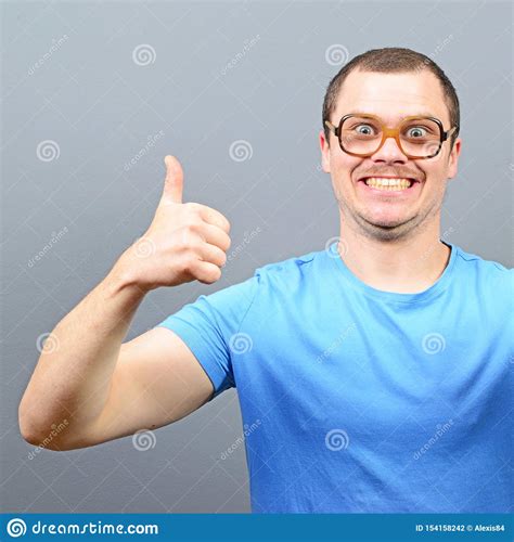 Portrait Of A Geek Showing Thumbs Up Against Gray Background Stock