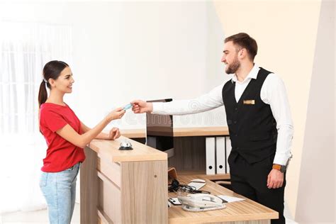Professional Receptionist Working With Client At Desk In Hotel Stock