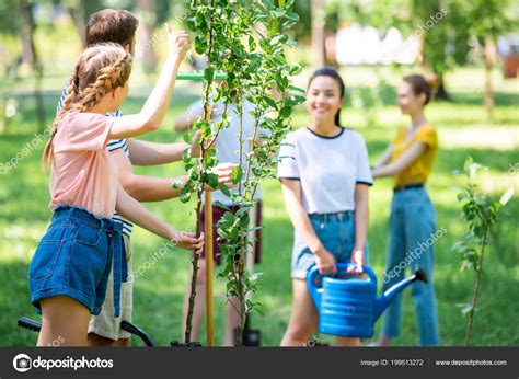 Young People Planting New Trees Volunteering Park Together Stock Photo