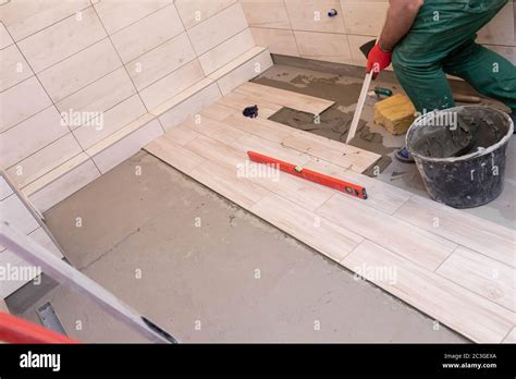 Professional Construction Worker Laying Ceramic Tiles On The Floor In