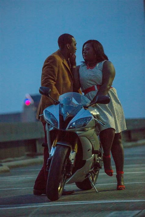 A Man And Woman Standing Next To A Motorcycle