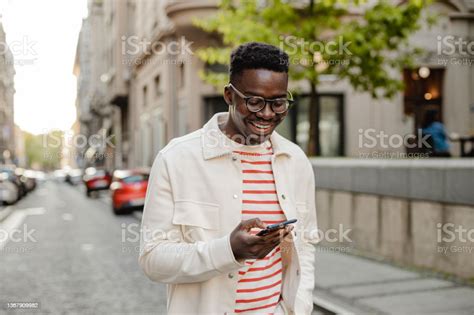 Young Africanamerican Man Uses A Mobile Phone On The Go Stock Photo